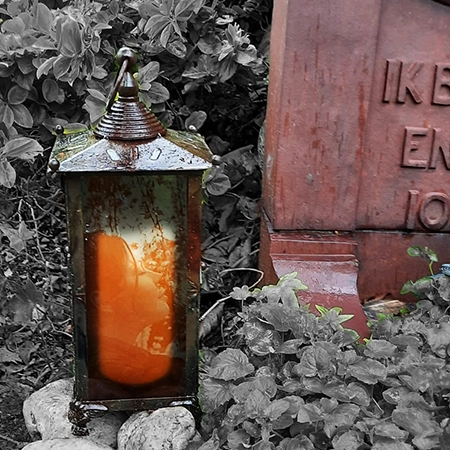 Portret in glas in een windlicht bij een grafsteen